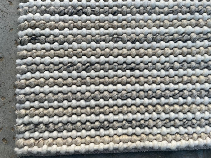 Textured rug with a pattern of interwoven yarn on a flat surface